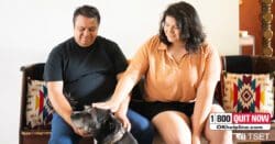 Kenneth Allen sitting inside with his daughter Logan and dog, looking into camera. Native American art and decorations in the background.